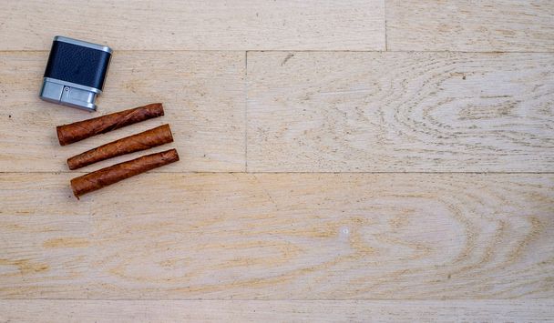 trois cigares toscans et un briquet sur un plancher de bois
 - Photo, image