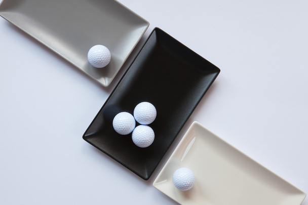 Different ceramic dishes with golf balls on over white backgroun - Fotó, kép
