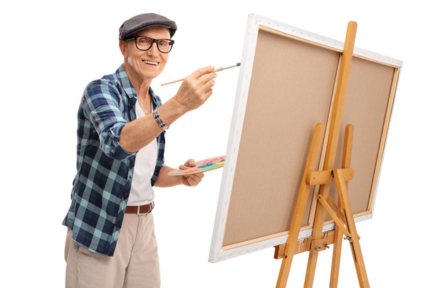 Joyful mature artist painting on a canvas  - Fotó, kép