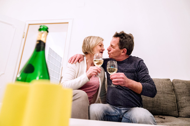Senior couple sitting in living room , drinking champagne, kissi - Foto, Imagem