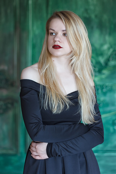 Elegant blonde in a black dress near grunge wall - Foto, imagen
