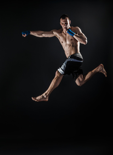 Muscular kickbox or muay thai fighter punching in jump. Smoke. - Fotografie, Obrázek