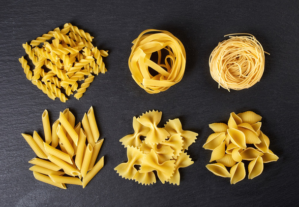 Verschillende soorten pasta op zwarte achtergrond, uit bovenstaande - Foto, afbeelding