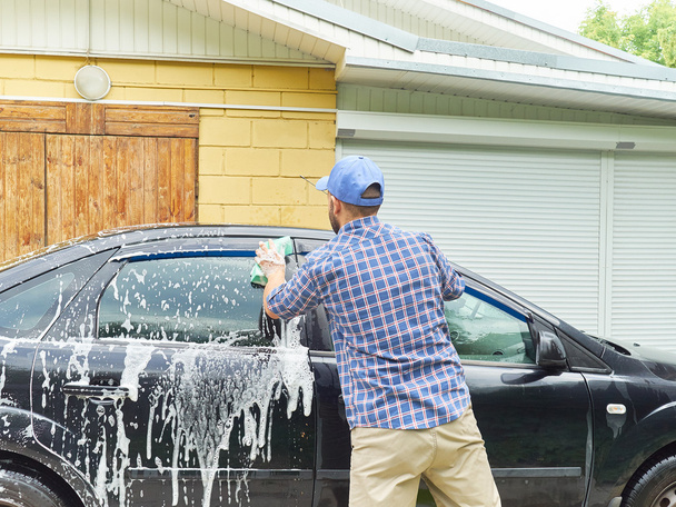 Homem lavando seu carro preto perto de casa
. - Foto, Imagem