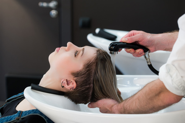 Jeune adolescente dans le salon de coiffure laver les cheveux par les mains des hommes coiffeurs
. - Photo, image