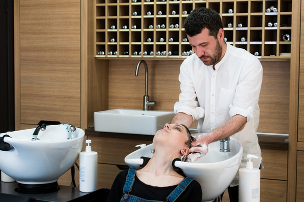 スタイリスト美容師で若い女性に頭を洗う - 写真・画像