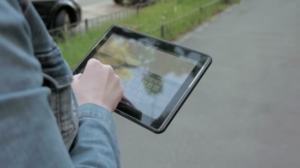 Kobieta typy tekstów na tablet pc chodzenie na zewnątrz - Materiał filmowy, wideo