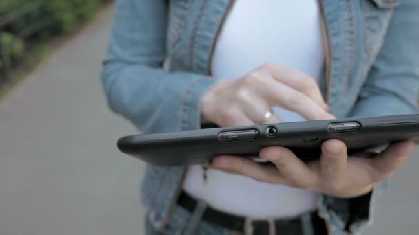 Mujer escribe textos en tableta PC caminando al aire libre
 - Imágenes, Vídeo