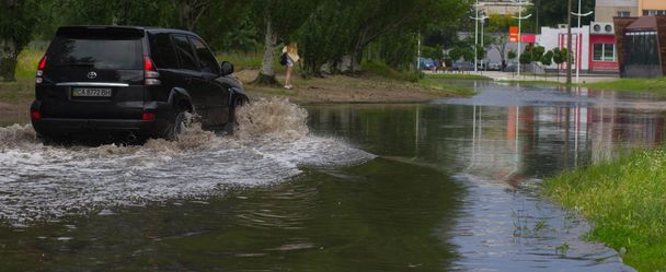 CHERKASSY, UCRAINA - 5 GIUGNO 2016: auto che guidano su una strada allagata durante un'alluvione causata da forti piogge, a Cherkassy
. - Foto, immagini