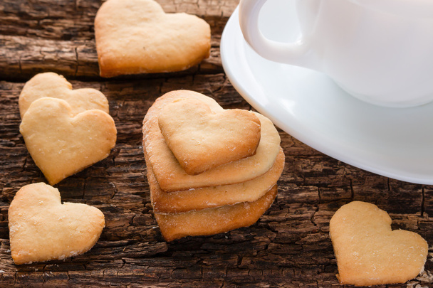 homemade cookies in the shape of heart and white cup on a wooden background - Foto, Imagen