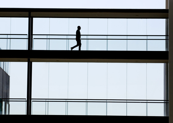 Silhouet weergave van jonge zakenman in een modern kantoorgebouw interieur - Foto, afbeelding