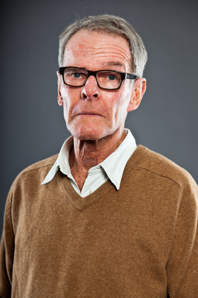 Expressive good looking senior man wearing glasses against grey wall. Funny and characteristic. Well dressed. Studio shot. - Fotó, kép