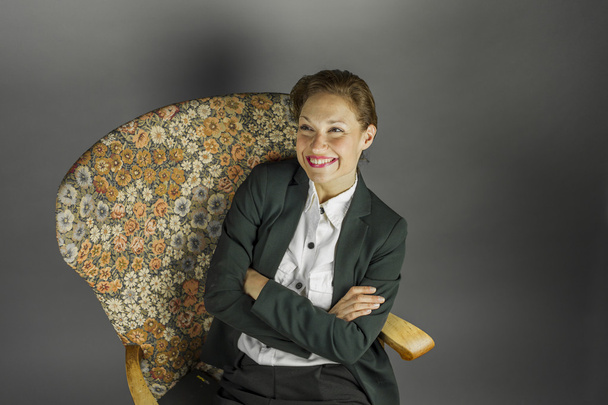 Young sensual woman in men's black suit sit in an armchair - Foto, afbeelding