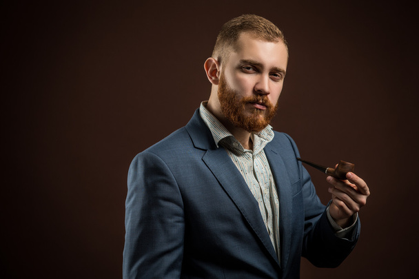 Elegant man with beard holding smoking pipe - Photo, image
