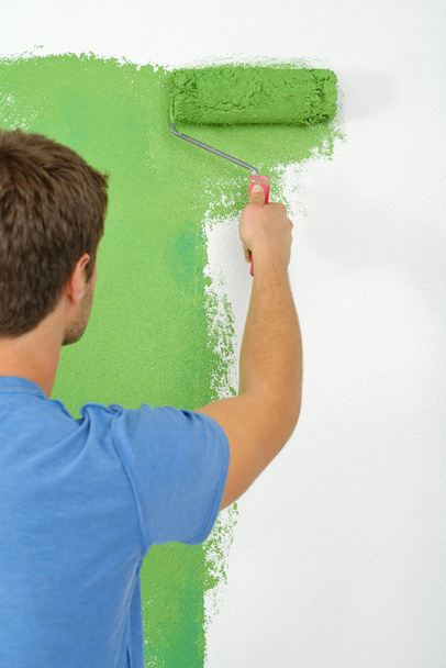 Handsome young man paint white wall in color - Photo, image