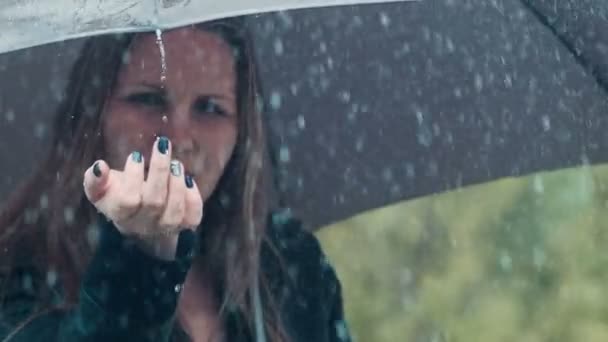 Blonde woman under umbrella toching drops of rain - Video