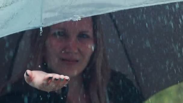 Blonde woman under umbrella toching drops of rain - Кадры, видео