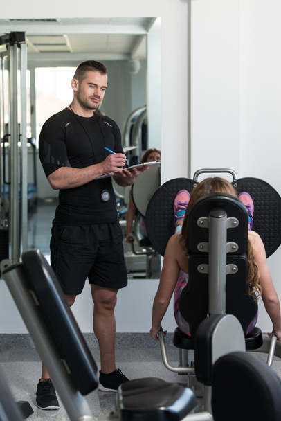 Personal Trainer ottaa muistiinpanoja, kun nainen harjoittelee jalat
 - Valokuva, kuva