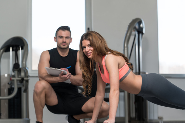 Personal Trainer Takes Notes While Woman Doing Push-Up - Foto, afbeelding