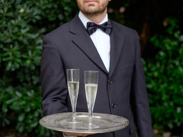 Профессиональный официант в форме подает шампанское
 - Фото, изображение