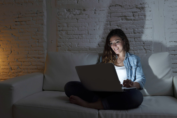 привлекательная расслабленная женщина дома сидит счастливая на диване с помощью ноутбука ночью
 - Фото, изображение