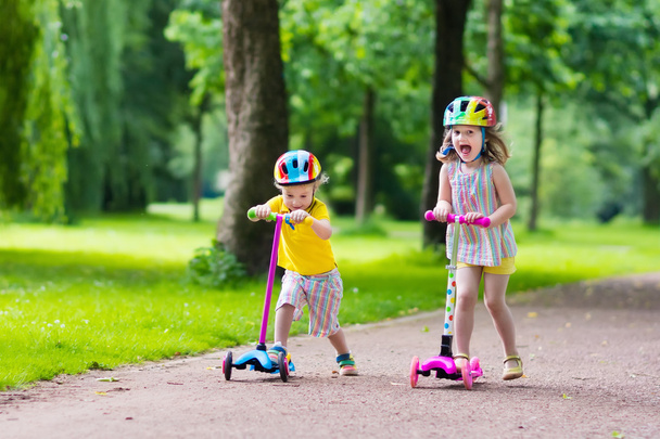 Маленькі діти катаються на барвистих скутерах
 - Фото, зображення