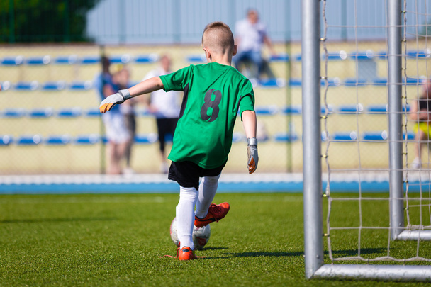 Młody chłopak piłka nożna bramkarz kopanie piłki nożnej na boisko sportowe. - Zdjęcie, obraz