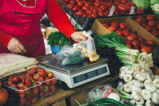 продавец взвешивает овощи на весах
 - Фото, изображение