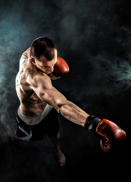 Muscular kickbox or muay thai fighter punching in smoke. - Valokuva, kuva
