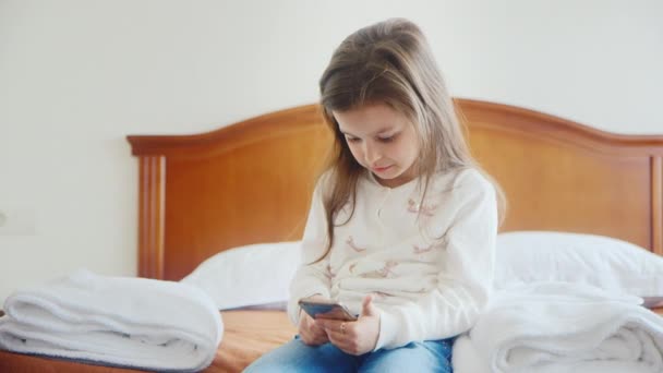 Girl 6 years old playing on a mobile phone in the hotel room - Filmmaterial, Video