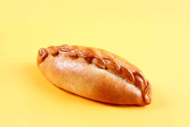 Fresh pie, bun with meat and vegetables on yellow background. Pastries and bread in a bakery - Photo, Image