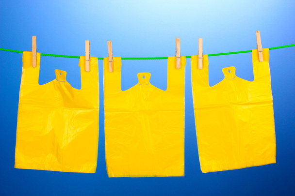 Cellophane bags hanging on rope on blue background - Foto, afbeelding