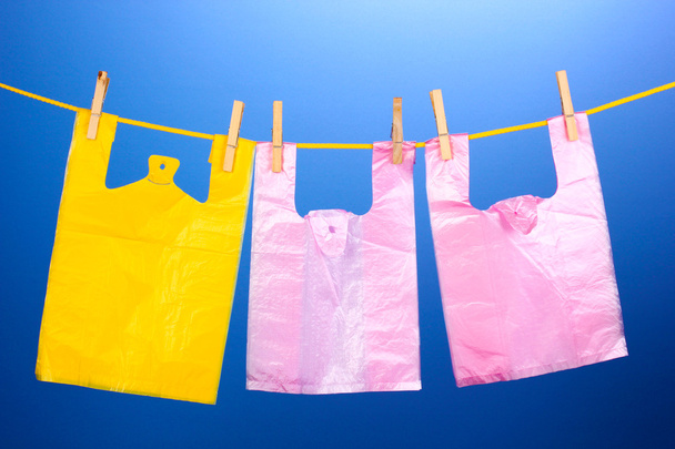 Cellophane bags hanging on rope on blue background - Foto, Bild