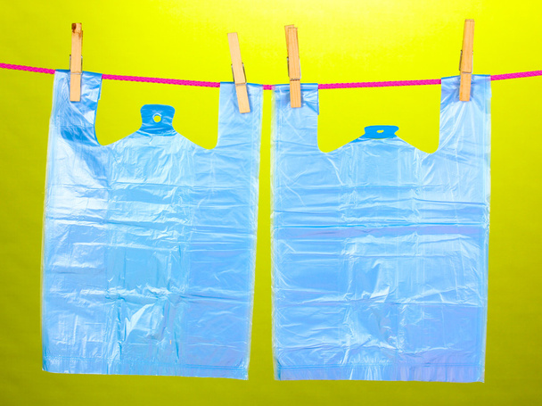 Cellophane bags hanging on rope on green background - 写真・画像