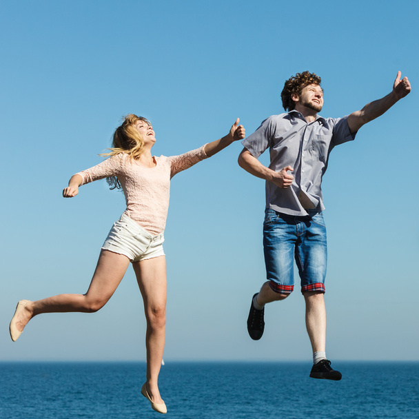 Carefree couple jumping by sea ocean water. - Foto, Imagen