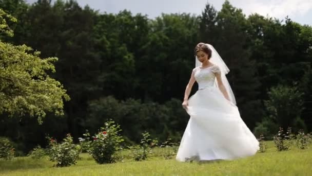 Beautiful brunette woman dancing and circling with bridal dress at the park - Footage, Video