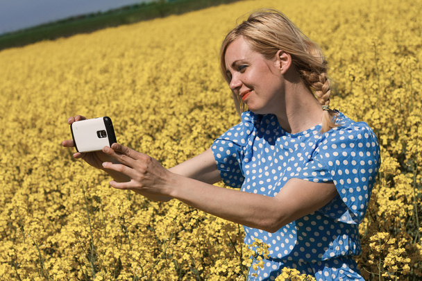 mujer rubia tomando una selfie en un campo de canola
 - Foto, imagen