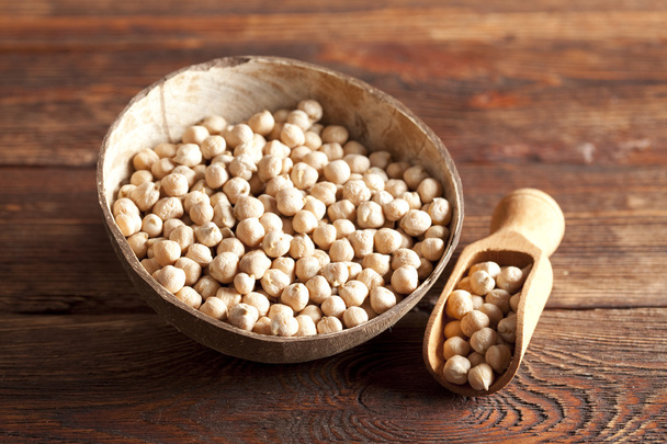 Chickpeas in bowl and scoop on wooden table - Photo, image