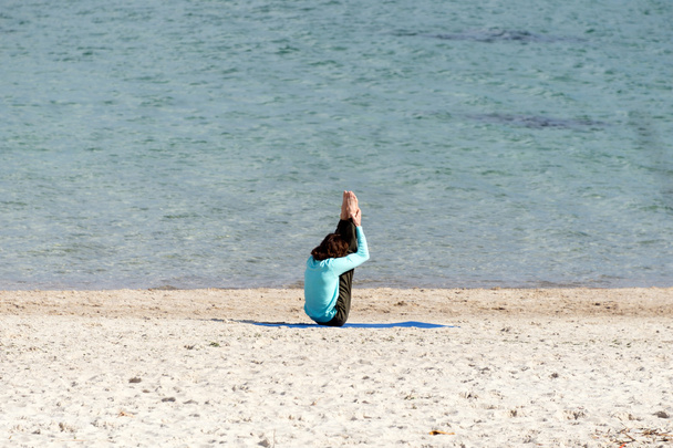 Uomo che fa yoga in riva al mare. Giovani che si allenano in spiaggia
. - Foto, immagini