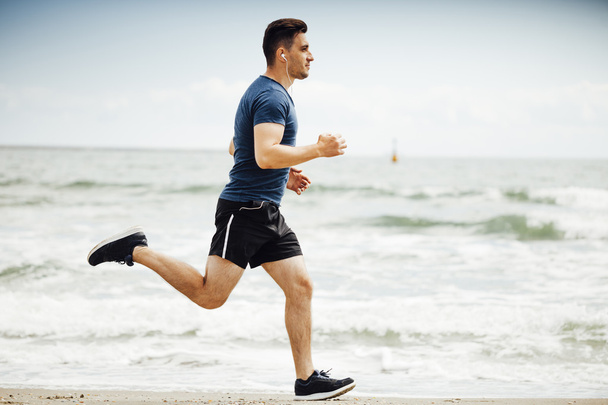 Man running on sunny beach - 写真・画像