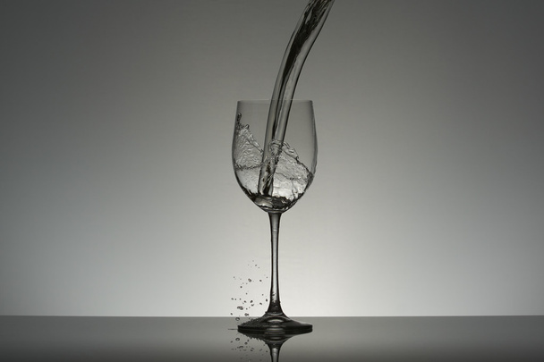 Falling water flow into a wineglass. - Valokuva, kuva