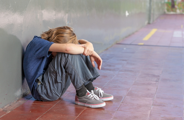 Um estudante sentado no chão da escola. Assédio moral e isolamento
 - Foto, Imagem