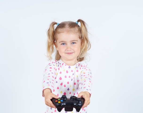 Маленька дівчинка грає у відеоігри з геймпад в руках
. - Фото, зображення