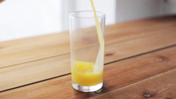 orange juice pouring into glass on wooden table - Filmmaterial, Video
