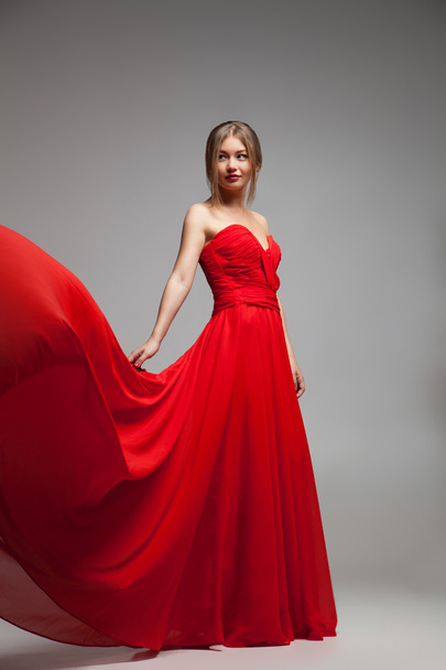 Beautiful model in red dress with flying skirt - 写真・画像