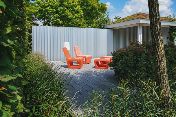 Два оранжевых стула с напольным лампом в зоне отдыха в парке
 - Фото, изображение