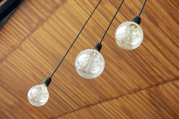 Τρεις ρετρό λάμπες φωτός κρέμονται από ξύλινη οροφή σε καφενείο - Φωτογραφία, εικόνα