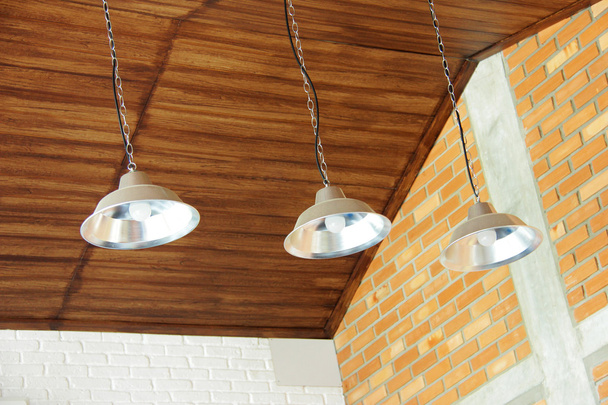 Три ретро лампочки, що звисають з дерев'яної стелі в кав'ярні
 - Фото, зображення