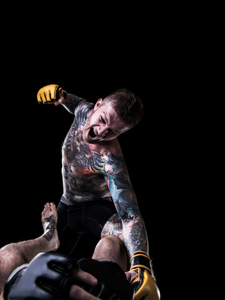 agressieve mma vechter bokszak tegenstander op de grond - Foto, afbeelding