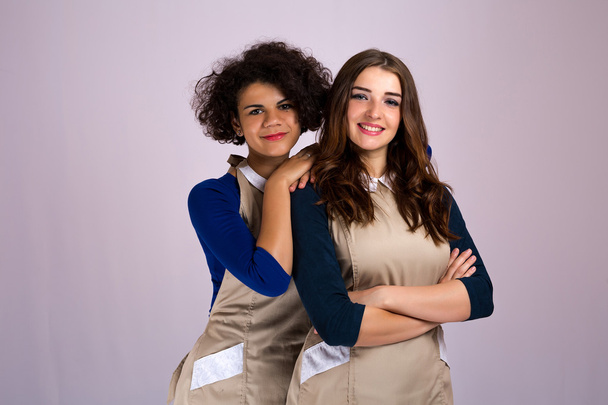 two nice girl from different nationalities Caucasian and Latina posing in studio in aprons . beauty industry - Photo, Image